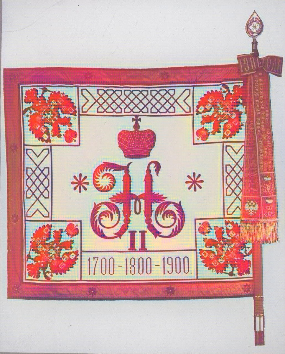 Новое полковое знамя 12-го гренадерского Астраханского Императора Александра III полка. 25 июня 1900 года. Даровано полку в честь празднования 200-летия данной воинской части. Колоризованное фото. Оргигинал по ссылке: https://humus.livejournal.com/9747015.html 25 июня 1900 года полк отмечал 200-летний юбилей. В этот день полку было пожаловано новое Георгиевское знамя с Александровской юбилейной лентой. На знамени были надписи, связанные с историческими событиями, такими как взятие Остроленки в 1831 году и победа под Плевной в 1877 году. Это событие стало важным этапом в истории полка, подчеркнувшим его заслуги перед Российской империей. Иконография: На знамени присутствовали вензеля императоров Петра I, Александра III и Николая II, подчеркивая преемственность традиций. Император Николай II - Августейший Шеф 12-го гренадерского Астраханского Императора Александра III полка с 25 июня 1900 года по 4 марта 1917 года. Таким образом, вручение знамени в 1900 году стало не только актом признания исторических заслуг, но и демонстрацией единства монархии и армии на пороге новых испытаний, включая Первую мировую войну.