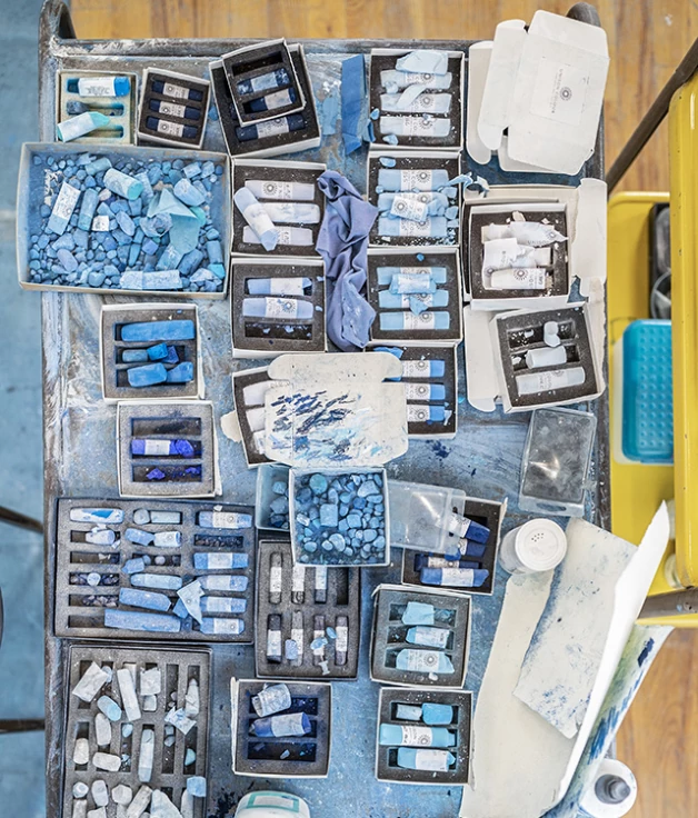 Тончайшая голубая пыль от этих мелков покрывает всю студию художницы и оседает на волосах Зарии во время работы 