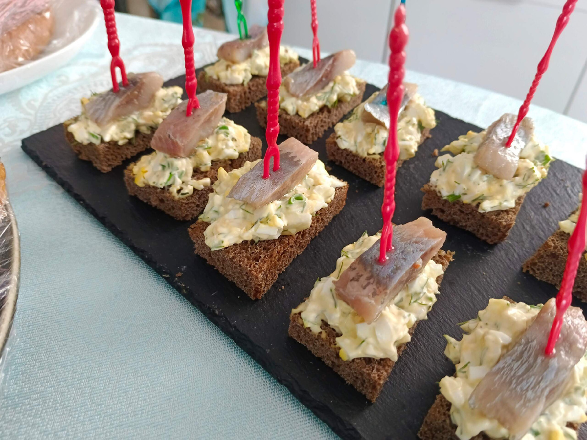 Ингредиенты:- яйца — 2 шт.;- майонез — 1 ст. л.;- чёрный хлеб — 3 кусочка;- зелёный лук — 4–5 перьев;- сельдь солёная — 1 филе;- соль — по вкусу. Приготовление пошагово:1. Отварить яйца в течение 10 минут после закипания воды, остудить, очистить и натереть на крупной тёрке в глубокую тарелку.2. Перья зелёного лука вымыть, мелко нарезать и добавить в тарелку с яйцами.3. Выложить майонез, перемешать яично-луковый салат, немного подсолить (сильно солить не нужно, так как будет выкладываться селёдка).4. У хлеба отрезать верхнюю чёрную корочку, разрезать каждый кусочек на 4 квадратика.5. На квадратики чёрного хлеба разложить яично-луковый салат. Всего получается 12 небольших бутербродов.6. Нарезать филе сельди на кусочки шириной 1–1,5 сантиметра.7. Выложить по кусочку селёдки на каждый бутерброд поверх яично-лукового салата.8. Разложить готовые бутерброды на плоскую тарелку, которую можно слегка присыпать нарезанным зелёным луком.#бутерброды #закуски #закуска #селёдка #бутербродысселёдкой #рецептбутербродов #закускасселёдкой #закускаизселёдкиДрузья. Подписывайтесь, чтобы не пропустить дальнейшие видео. Ставьте лайк. Пишите комментарии. Приятного аппетита.