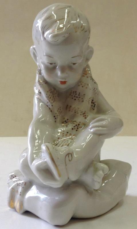 "Мальчик, надевающий сандалии" ("Мальчик с шарфом"), модель 1958-го года.  Фарфор, роспись надглазурная (полихромная), роспись золотом. Размеры: 14,5*11,5*10,0 см. Государственное автономное учреждение культуры Ярославской области "Ярославский художественный музей".