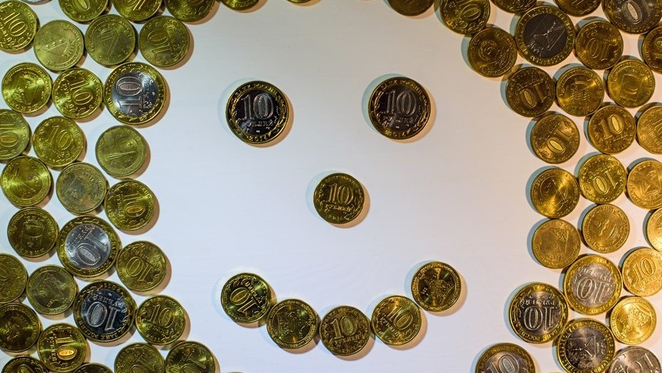    Смайлик, выложенный на белом столе из монет номиналом 10 рублей. Автор фото: Сергей Ермохин / "Деловой Петербург"