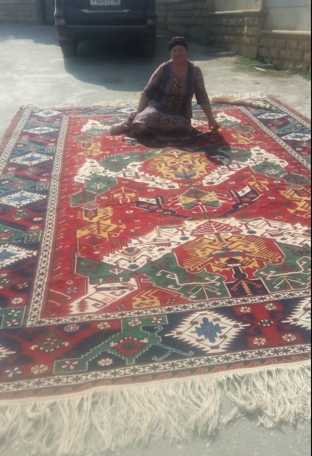 Бесира Мусаева во дворе сидит на сумахе, который она соткала в 2005 году. 