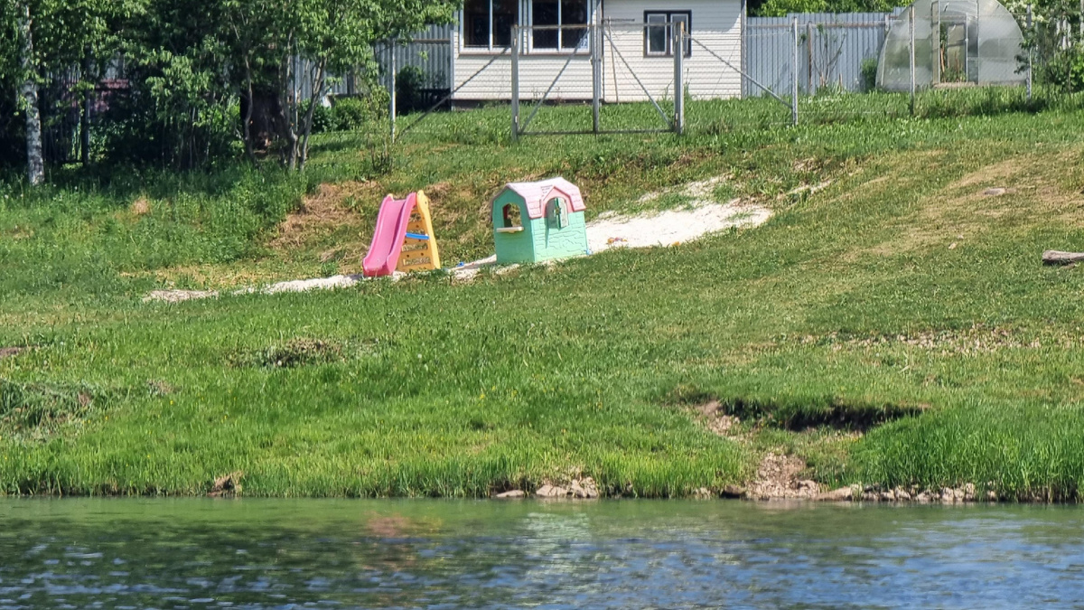 Дачные домики уютно расположились по берегам, а прямо у воды – детский домик и горка.