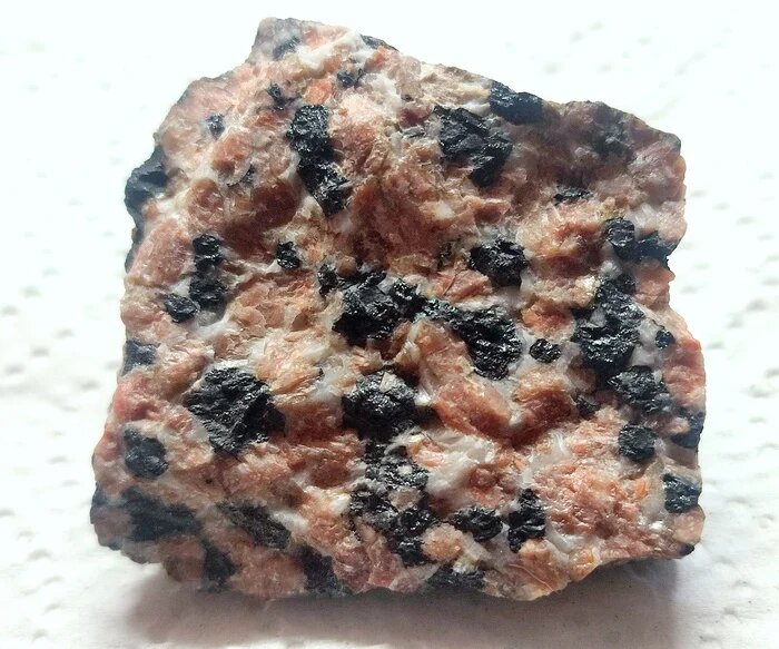 Образец виллемита (розоватое) с кальцитом (светло-серое) и франклинитом (черное) при обычном свете. Месторождение Франклин, Houghton County, Michigan, USA. Из собрания автора