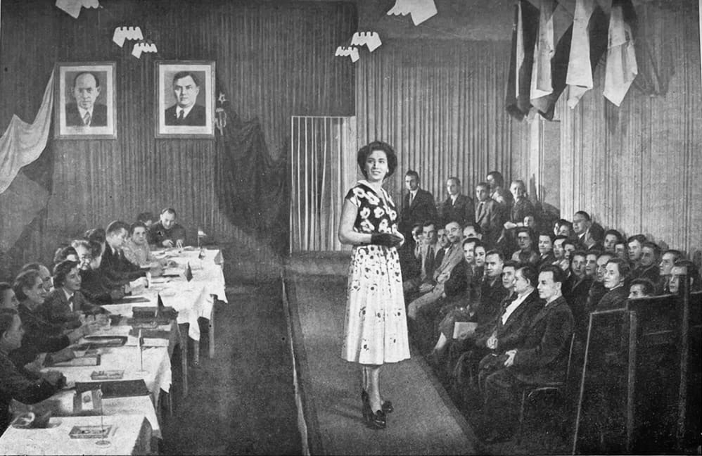 Заседание жюри на международном конкурсе в Праге на лучшую модель одежды. Слева - руководители стран-делегаций, справа - гости. На подиуме модель в платье от Общесоюзного дома моделей (г. Москва). Фото из статьи.