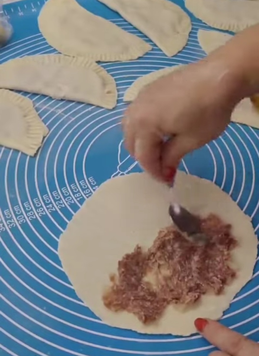 4. Аккуратно распределите фарш тонким слоем ближе к центру.5. Закрывайте вторую половину теста поверх фарша, аккуратно прижимая края друг к другу пальцами.6. Скрепляйте края, используя вилку, плотно придавливая краешки.