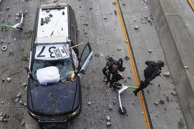    Сотрудники дорожного патруля пытаются увернуться от камней во время погромов в центре Лос-Анджелеса, штат Калифорния, США, 8 июня 2025 года. Фото: Jae C. Hong / AP