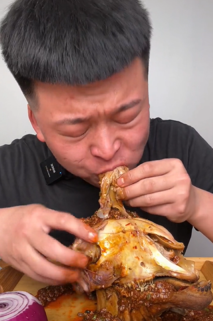 Китаец ест баранью голову с острым соусом, заедая луковицей. Кадр из китайского ролика.