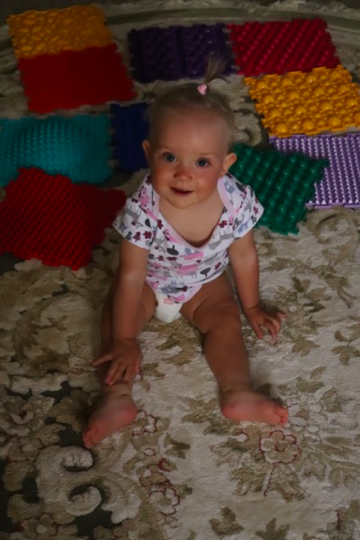 Екатрине 10 семяцем - сидит отдыхает, после упражнений, на коврике. 