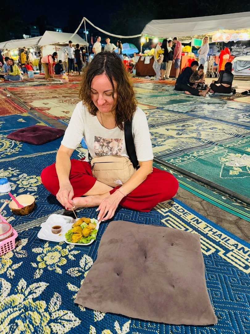 На ночном рынке в Пномпене, столице Камбоджи, едят, сидя на ковриках и подушках