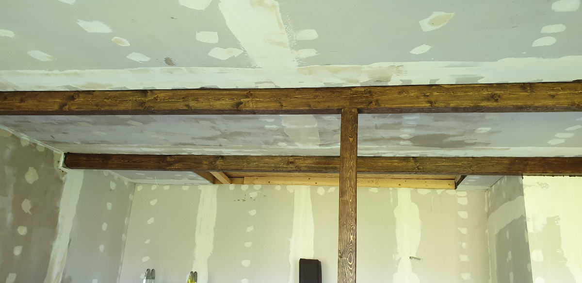 Стыки гипса и следы от саморезов зашпатлеваны, балки покрашены Пинотексом