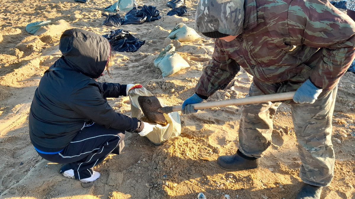 Счищаем мазут с песка и в мешок...