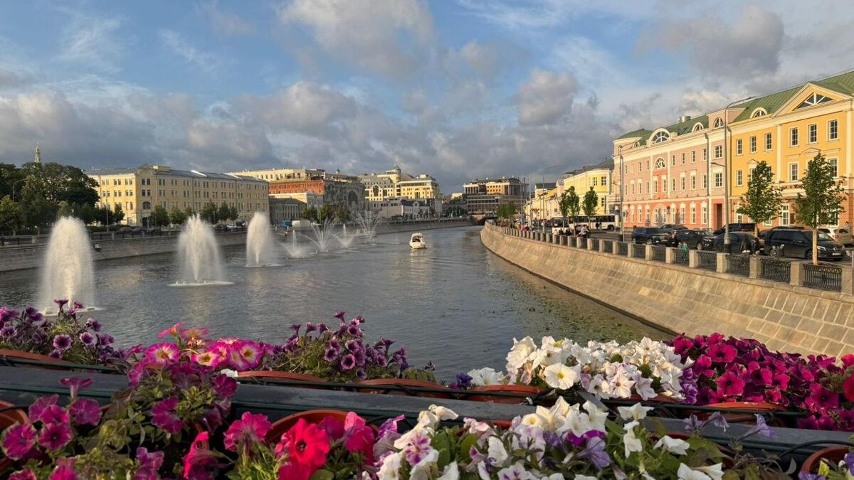 Фонтаны на Москве-реке и мост с цветами на фоне летнего неба