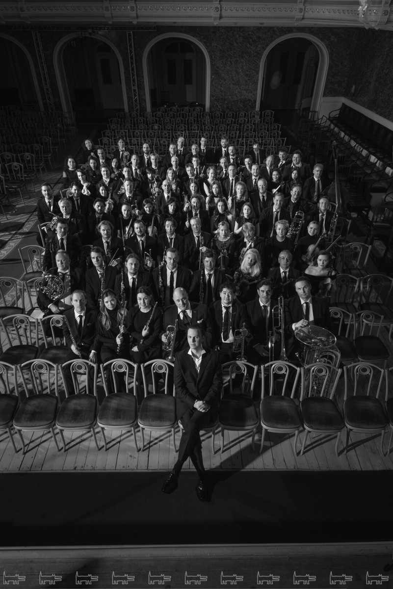    Теодор и музыканты musicAeterna сфотографированы в зале Государственной академической капеллы. На время реконструкции Дома Радио Капелла, построенная архитектором Леонтием Бенуа в 1889 году, стала одной из постоянных площадок для выступлений коллектива Снизу-вверх, слева-направо: Теодор Курентзис, Федор Чернышов, Маргарита Галкина, Анна Комарова, Павел Курдаков, Жасулан Абдыкалыков, Жерар Костес, Иван Сватковский, Станислав Авик, Александр Быков, Данила Лукьянов, Данила Янковский, Никита Ваганов, Елена Иванова, Армен Погосян, Мария Стратанович, Андрей Ефимовский, Дмитрий Бородин, Алексей Никифоров, Фрол Герасимов, Артемий Савченко, Ольга Артюгина, Дмитрий Чепига, Мария Зорина, Анастасия Рыбина, Леонид Вознесенский, Талгат Сарсембаев, Елена Райс, Екатерина Горелова, Луиза Минцаева, Станислав Михайловский, Мария Окунева, Кристина Таха, Владимир Кищенко, Андрей Салтанов, Игорь Ахсс, Раббани Алдангор, Марина Антонова, Никита Истомин, Дилявер Менаметов, Любовь Лазарева, Евгения Гранова, Елена Харитонова, Дмитрий Клеменок, Андрей Бараненко, Мария Сагадиева, Александр Левко, Николай Дубровин, Алексей Сакович, Анастасия Стрельникова, Григорий Чекмарев, Ирина Сопова, Лев Серов, Петр Чонкушев, Айсылу Сайфуллина, Элина Лебедзе, Андрей Шинкевич, Анна Шугалева, Ольга Чукова, Динара Муратова, Роберт Брем, Андрей Сигеда, Иван Субботкин, Александр Котельников, Владислав Песин, Мириам Пранди, Алексей Жилин, Владимир Словачевский, Екатерина Романова, Максим Ходырев, Вадим Тейфиков, Никита Макин, Иван Иванчик, Павел Степин, Андрей Росцик, Андрей Сердюковский, Наил Бакиев, Всеволод Гузов, Александр Прозоров, Евгений Румянцев Фото: Валентин Блох