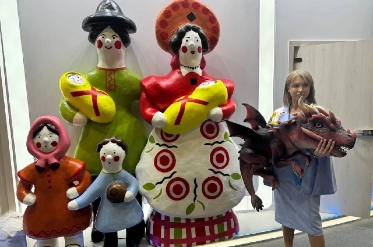    Телеведущая обратила внимание на игрушечного ящера на стенде Кировской области..