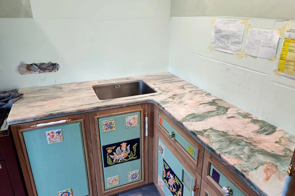 Вид кухни после монтажа столешницы. За счет неоднородности цвета она отлично сочетается и с кухонной мебелью, и с плиткой на полу