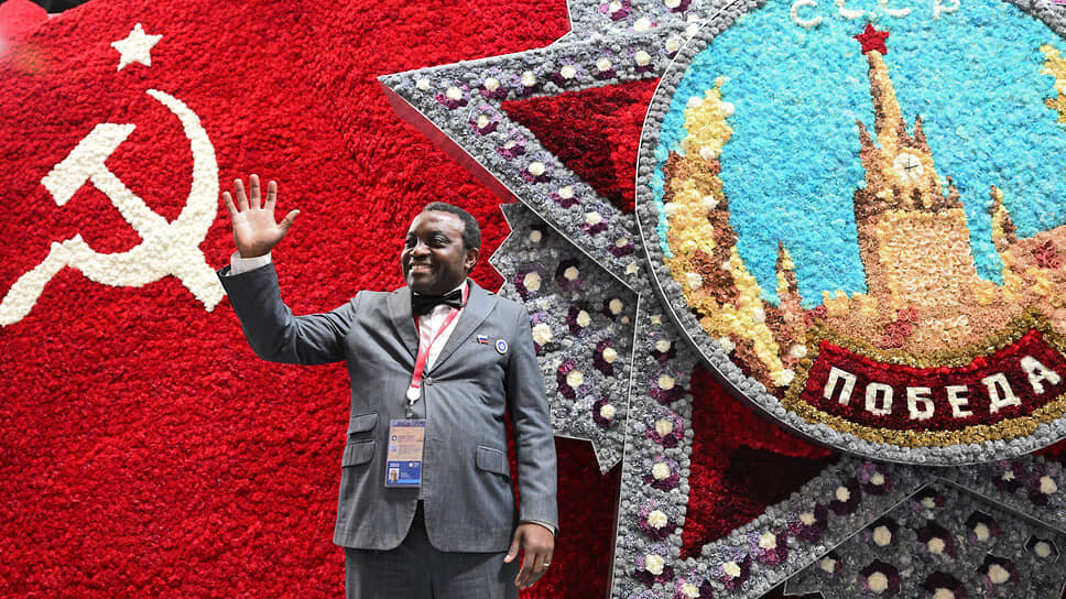 Участник форума фотографируется на фоне созданного из цветов ордена «Победы».📷Фото: Глеб Щелкунов / Коммерсантъ