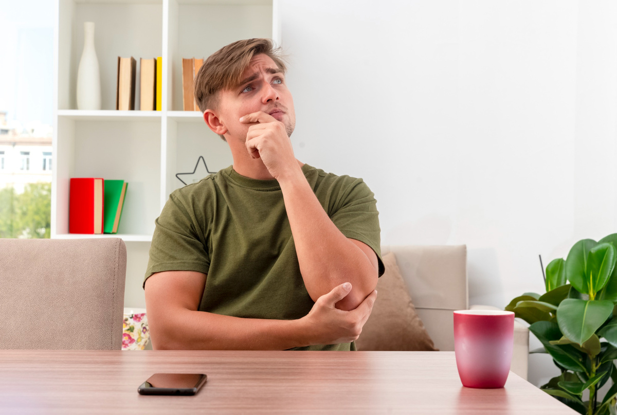 Источник: https://www.freepik.com/free-photo/thoughtful-young-blonde-handsome-man-sits-table-with-phone-cup-holding-chin-looking-up-inside-living-room_13464739.htm