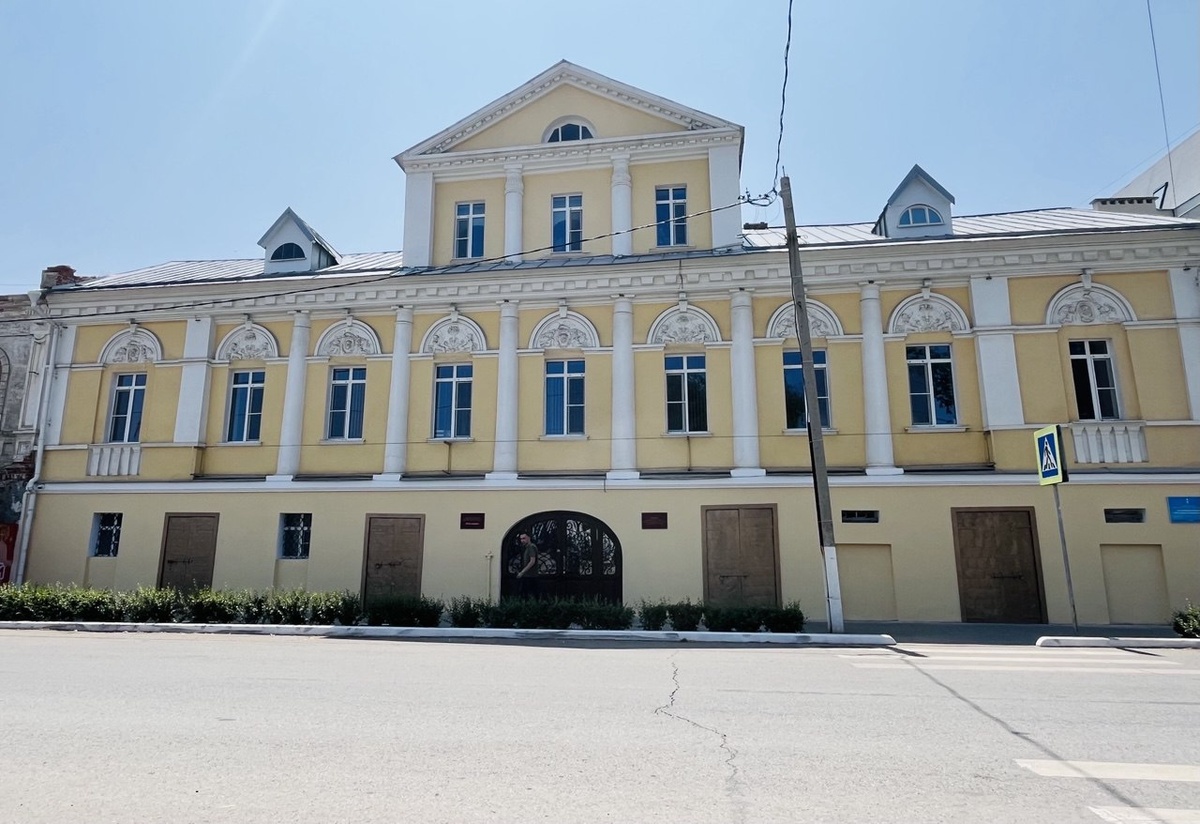 Вид на главный фасад здания с улицы. Элегантная симметрия, белоснежные колонны и жёлтая штукатурка создают торжественный облик усадьбы, достойный купеческой фамилии.