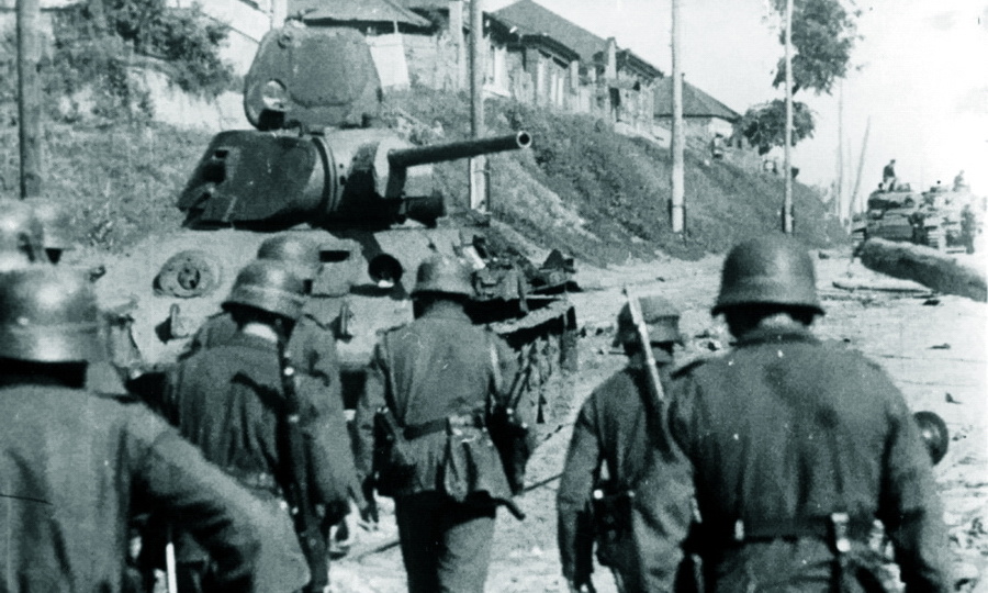 Немецкие солдаты проходят мимо советского танка Т-34, подбитого на улице 20-летия Октября в Воронеже