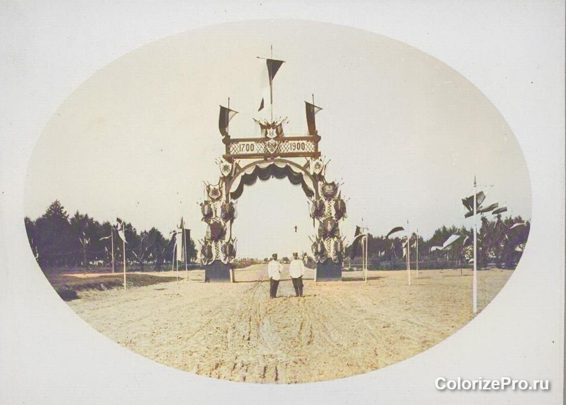 Юбилейная триумфальная арка в честь 200-летия 12-го гренадерского Астраханского Императора Александра III полка в летнем полевом лагере под Ярославлем 25 июня 1900 г. Фото колоризованное. Источник: Государственный исторический музей. "Нижние чины полка. Неизвестный фотограф. 1900 г.". Ссылка: https://catalog.shm.ru/entity/OBJECT/2443083?page=4&query=12-й%20гренадерский%20Астраханский%20полк&index=157