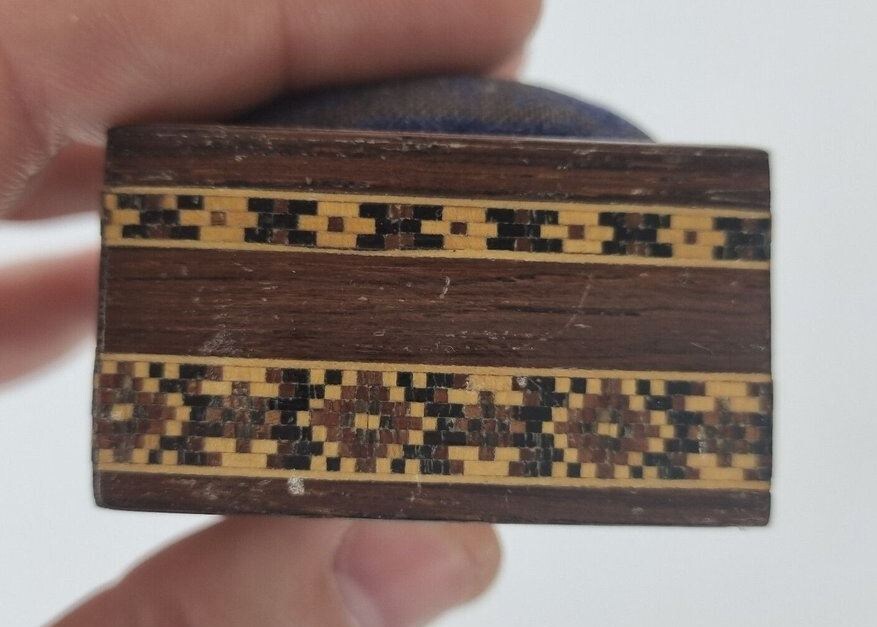 Старинная инкрустированная деревянная шкатулка-подушечка для иголок Tunbridge Ware.
Размеры приблизительно 7,3 см в ширину; 4,7 см в глубину; 3 см в высоту. Фото: https://www.wheelerantiques.co.uk/