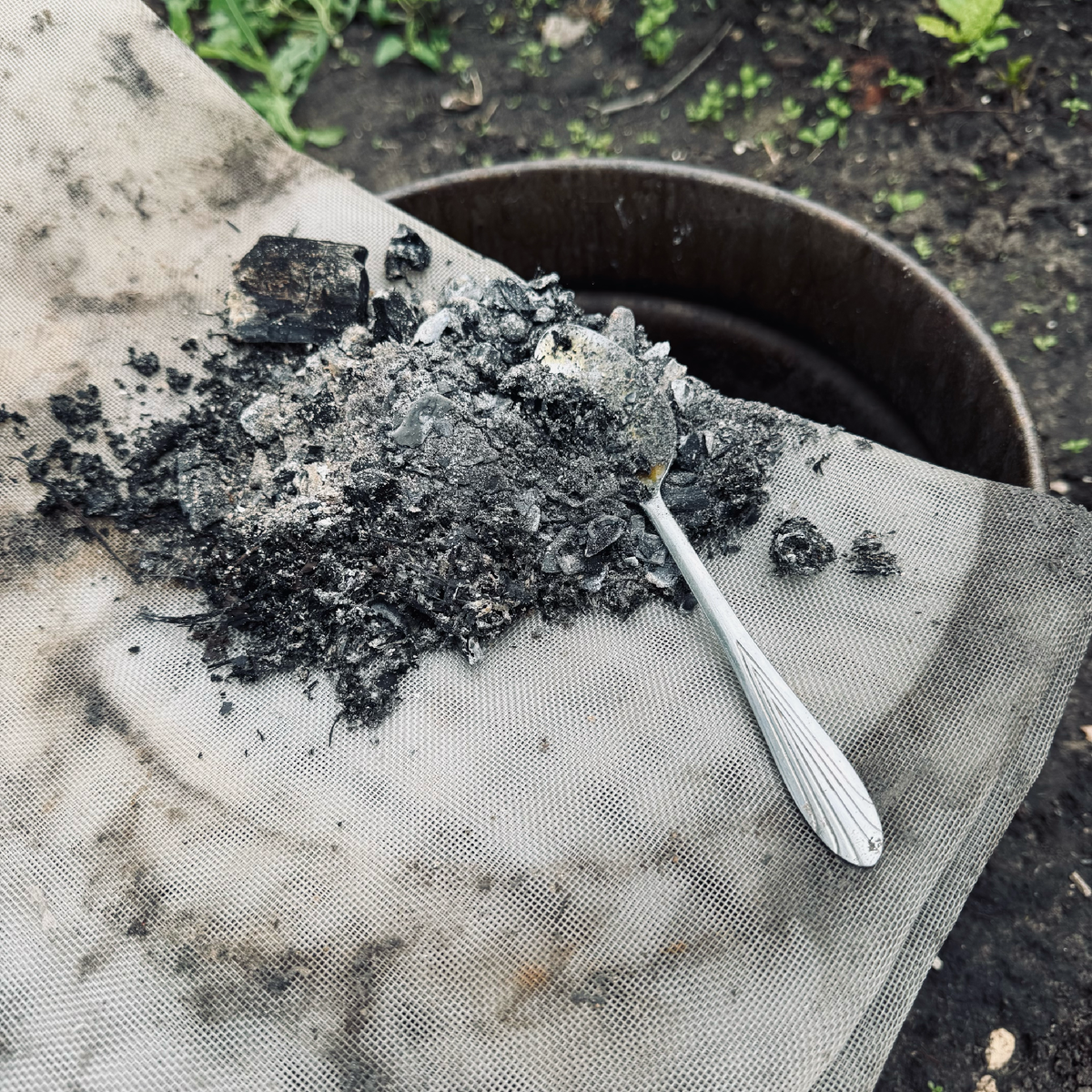 Просеиваю золу с помощью старой сетки