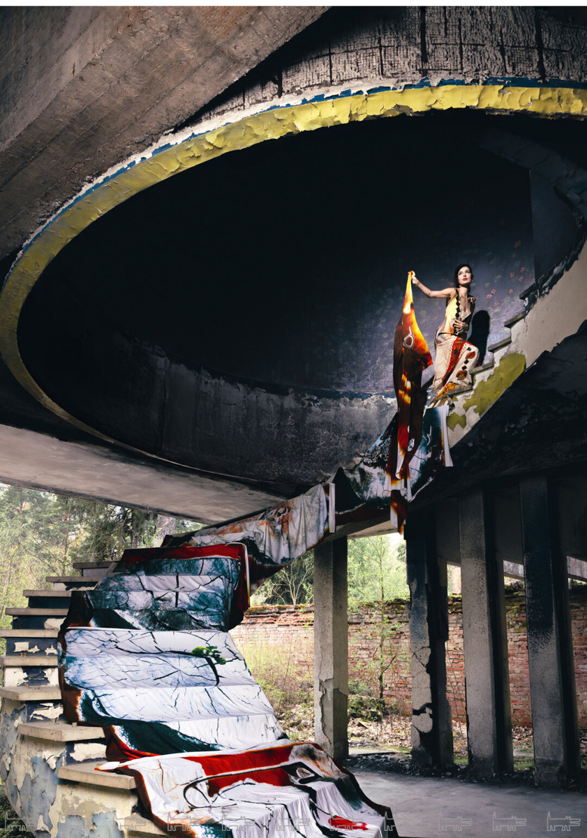    Кристина сфотографирована в здании бывшего кинотеатра санатория «Северная Ривьера» на берегу Финского залива в Зеленогорске. Классический советский санаторий с модернистской курортной архитектурой середины 70-х в ближайшие годы ожидает реконструкцию. На Кристине — арт-платье «Зов. На четыре стороны света» художника Вадима Тишина, дополненное 20-метровым расписным полотном