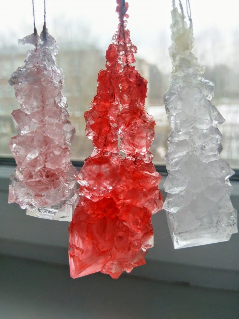 Три разноцветных кристалла, выращенных в рамках домашнего научного эксперимента, подвешены на нитях