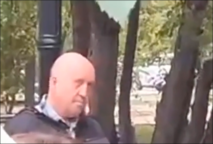    КАМЕРА СЛОВНО НАРОЧНО ВЫХВАТЫВАЕТ СКВОЗЬ ТОЛПУ ШКОЛЬНИКОВ СТОЯЩЕГО В ОТДАЛЕНИИ МУЖЧИНУ С ХАРАКТЕРНОЙ ВНЕШНОСТЬЮ. СКРИНШОТ: СОЦСЕТИ