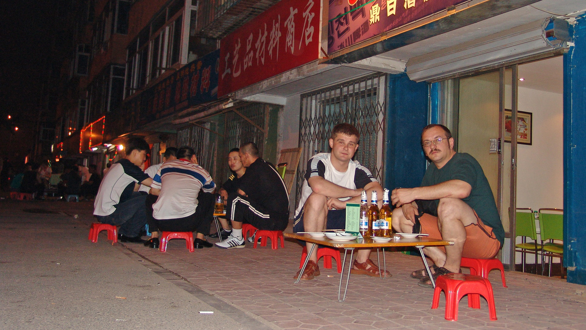Вечерние посиделки с пивом у кафе в Шеньяне. Мы так и не поняли, почему все отдыхают практически на корточках? Фото Константина Куликова