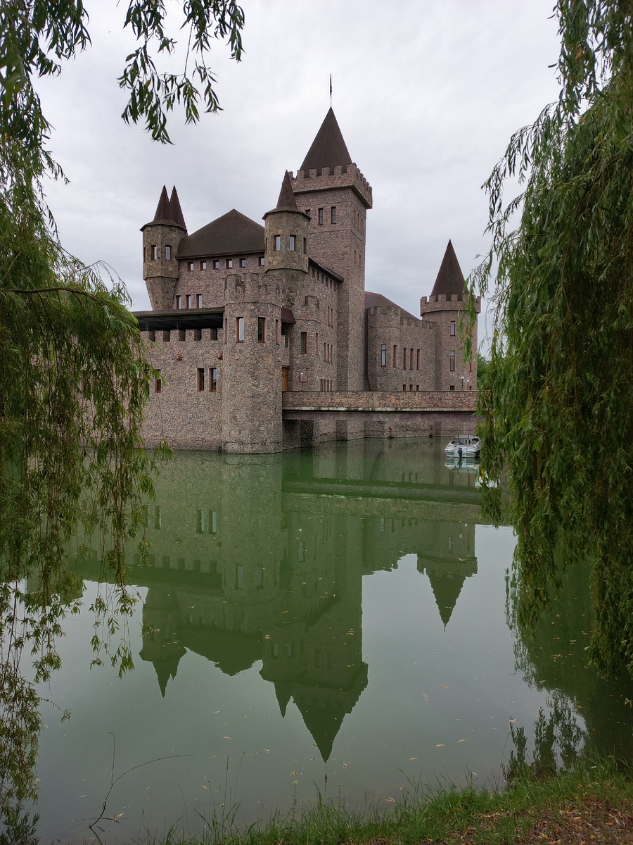 Необычный замок, выполненный в стиле средневековья, стоит посередине рукотворного пруда, как-будто плывет по воде. С погодой нам не очень повезло, было пасмурно и немного накрапывал дождь, но впечатления это не испортило.