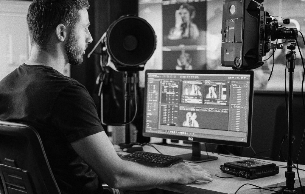 режиссер монтажа, который работает за компьютером в студии.