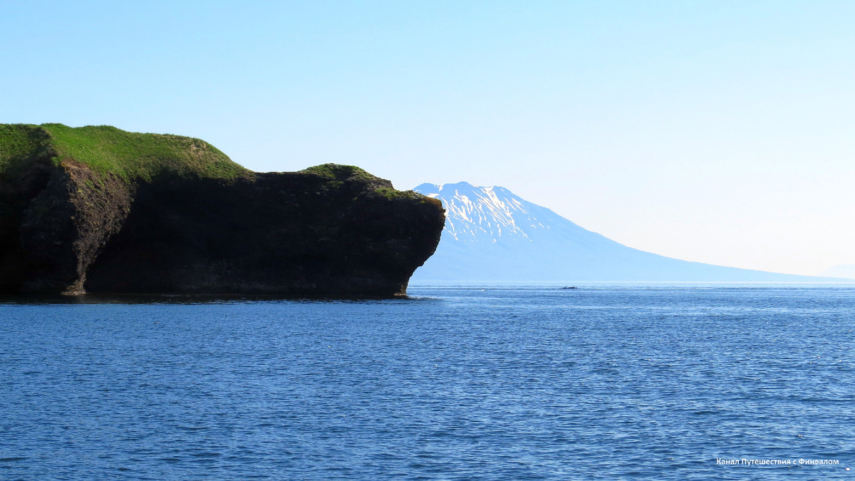Мыс Пржевальского, походий на медвежонка, на фоне заснеженного вулкана Стокап.