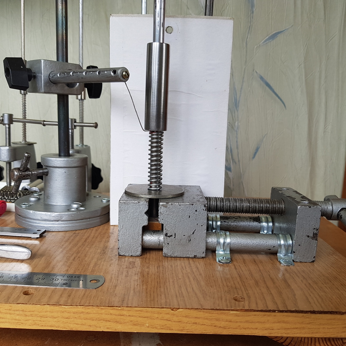 На этом снимке показаны крупным планом, как уже полностью подготовленная к работе чертилка, так и лежащий на пружине цилиндр с пока еще не закопченной поверхностью. За ними специально временно установлен в качестве фона просто белый экран для того, чтобы чертилка была видна более четко.