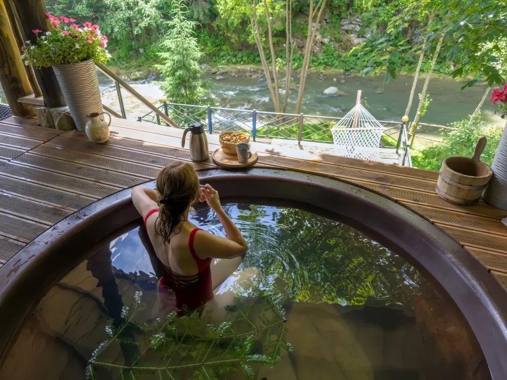 Девушка в купели с видом на реку — спокойствие и уединение в горах.