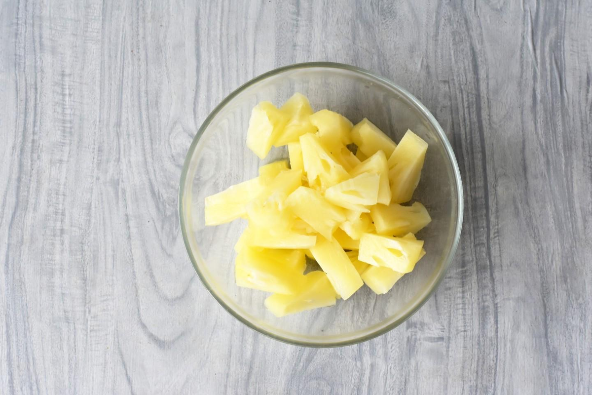 Консервированные ананасы выньте из банки, отряхните от влаги и нарежьте кусочками.