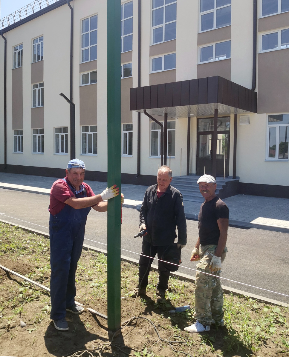 Строители Мухамед Копсергенов, Мухамед Шереметьев, Заур Копсергенов (слева направо) за установкой ограждения спортплощадки. Фото автора.