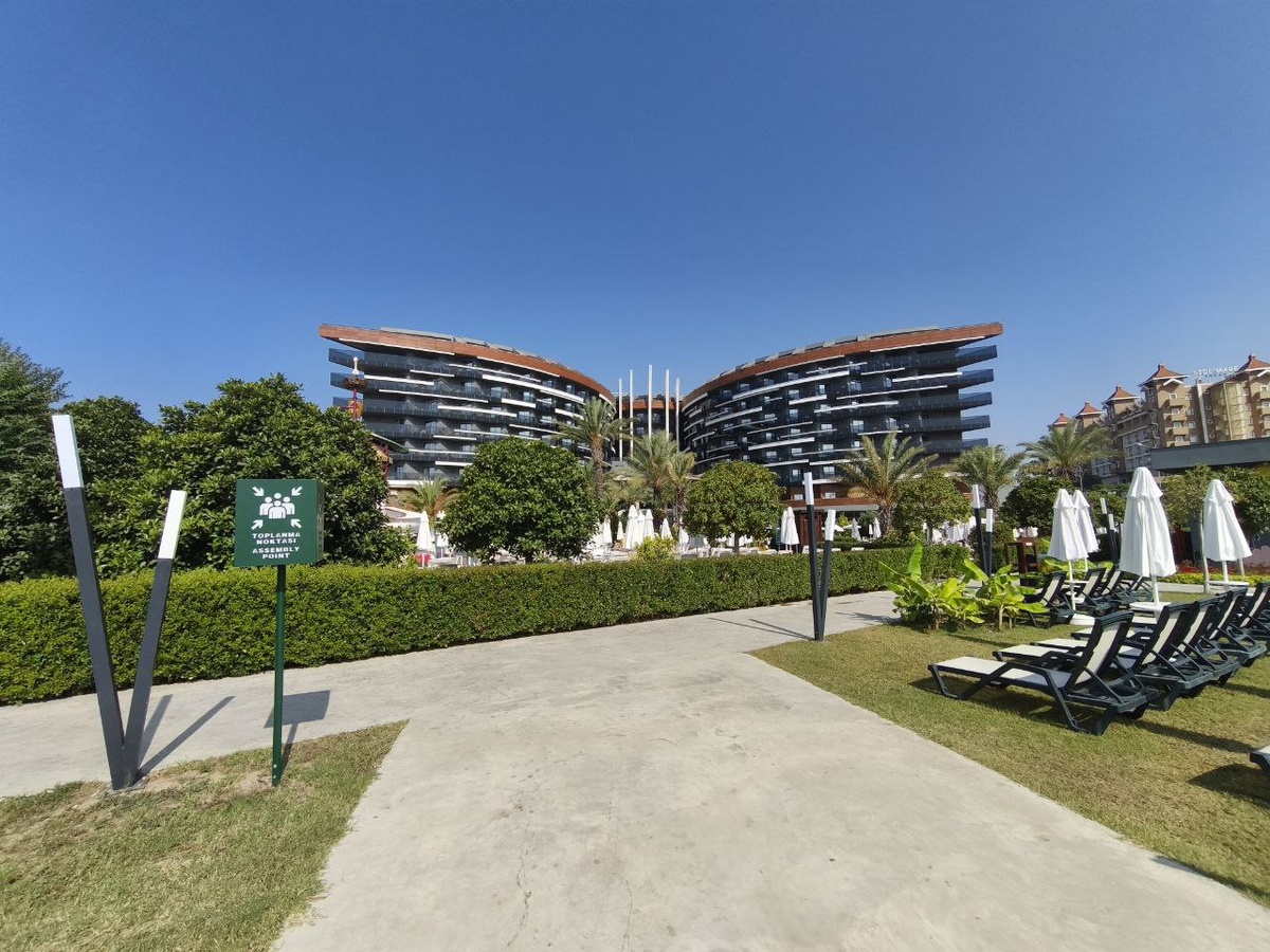 Вид на отель с лужайки с лежаками для любителей тишины. Отель похож на бабочку