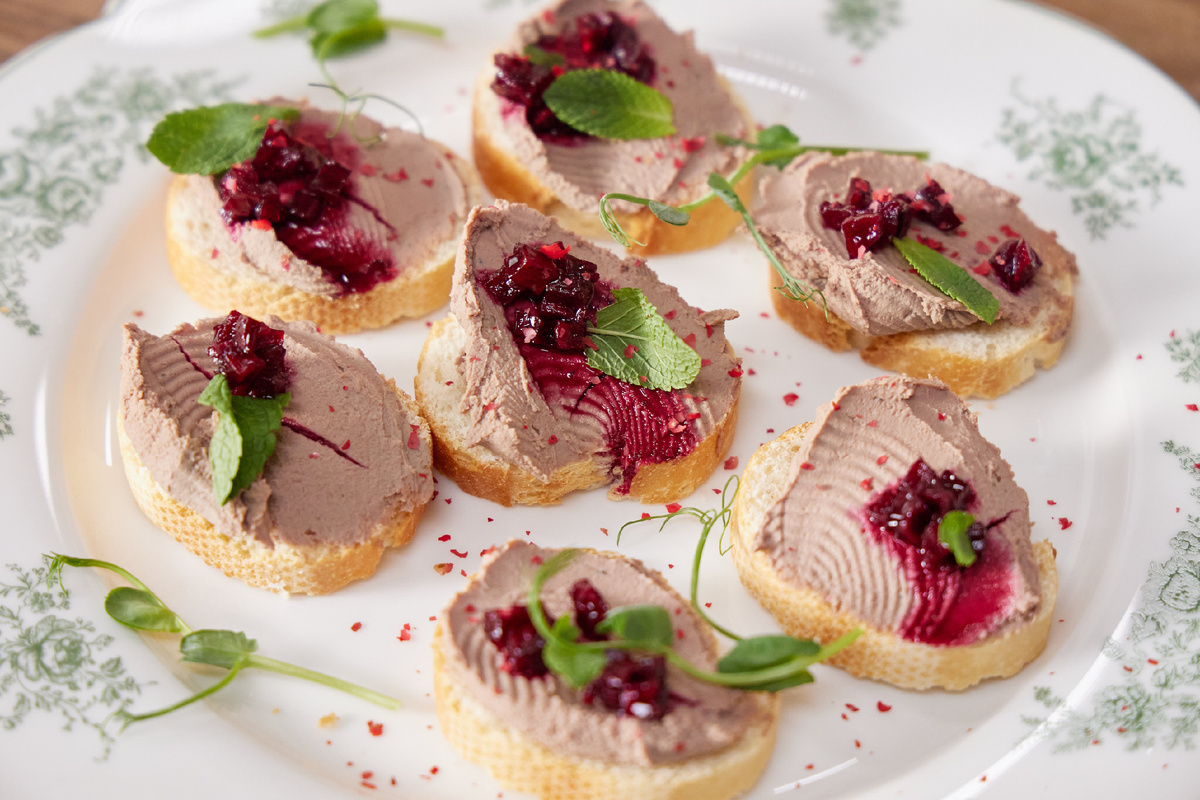 Ингредиенты:
Печень индейки — 400 г
Лук — 1 шт.
Сливочное масло — 60 г
Сливки 33% — 200 мл
Свёкла крупная — 1 шт.
Мёд — 1 ст. ложка
Яблочный уксус — 40 мл
Вода — 200 мл
Имбирь корень — 10 г
Гвоздика молотая — ¼ ч. ложки
Подсолнечное масло — 20 мл
Багет пшеничный — 1 шт.
Соль, перец — по вкусу

Для подачи: мята, розовый перец горошком, микрозелень

Приготовление:
1. Обжарить лук на подсолнечном масле до золотистого цвета, добавить печень индейки, обжарить 3 минуты. Влить сливки, посолить, поперчить, томить на медленном огне, добавить воду и сливочное масло. После - снять с огня.
2. Свёклу разделить: одну половинку нарезать кубиками для чатни, вторую натереть и отжать сок. 
3. Добавить 3 ст. ложки свекольного сока в печень, затем - измельчить блендером до паштетообразной консистенции, охладить в холодильнике минимум 3-4 часа.
4. Для чатни свекольные кубики тушить с яблочным уксусом, мёдом, водой и имбирём 20 минут, добавить гвоздику, охладить.
5. Нарезать багет, намазать паштет, сверху выложить чатни, украсить мятой, розовым перцем и микрозеленью.

Приятного аппетита!