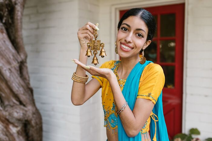 Источник: https://www.pexels.com/photo/woman-in-yellow-and-blue-sari-holding-a-gold-ornament-7686361/