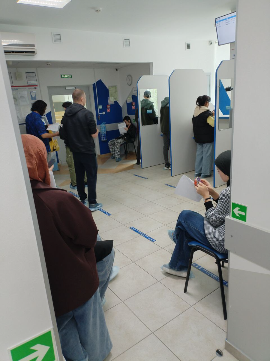 Перед окошками регистратуры относительно свободно, а в коридорах столпотворение