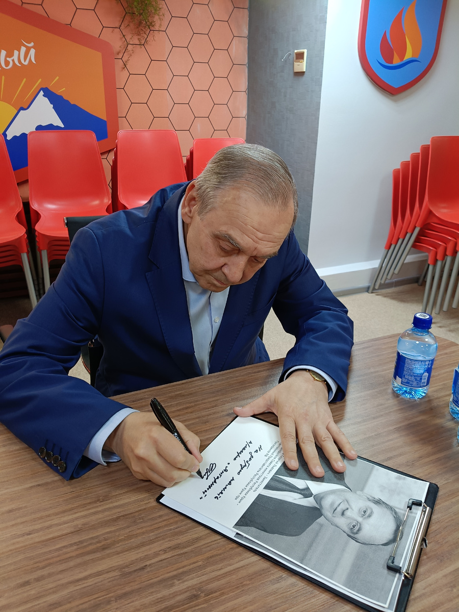 Георгий Мурадов оставляет автограф на фотографии 