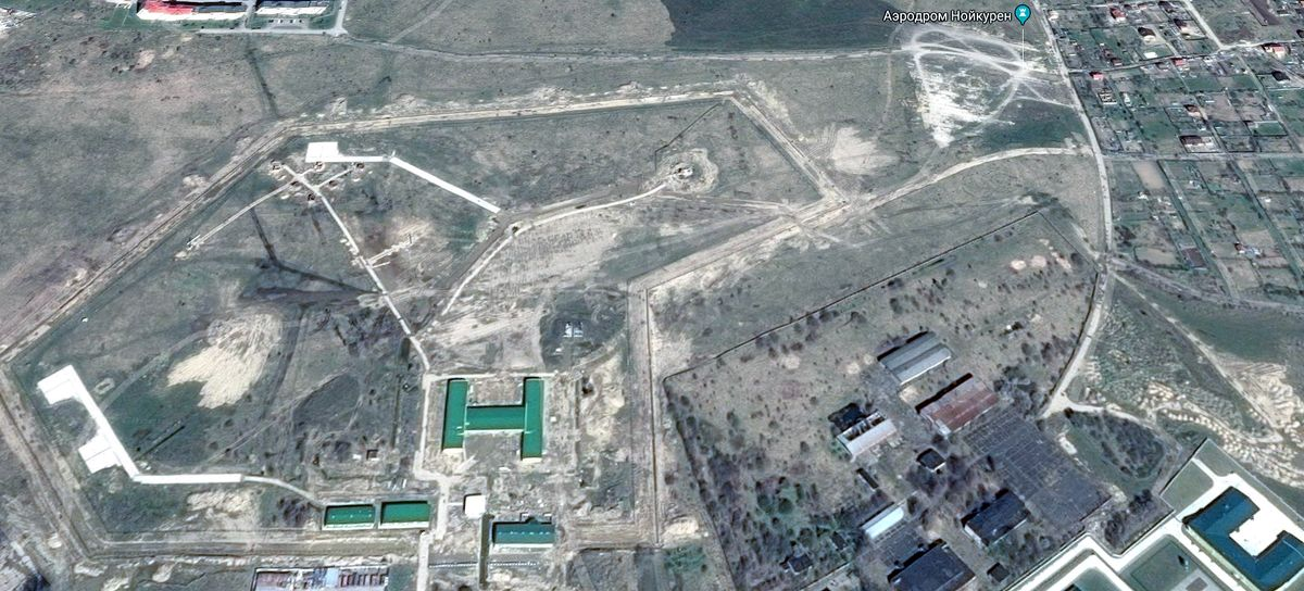 Фотоиллюстрация: Аэродром Нойкурен (южная часть). Здание в центре в форме буквы "Н" и рядом с ним - это современные здания военных частей и служб. Семиугольная широкая полоса из прямых участков - ВПП (взлётно-посадочная полоса) и рулёжные дорожки аэродрома Нойкурен. Современные здания с белыми прямоугольными дорожками в правом нижнем углу снимка - это район бывших казарм аэродрома Нойкурен и 9-го Флотского экипажа в ноябре-декабре 1971 года.
