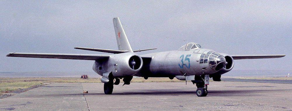 Фотоиллюстрация: 1971. Ил-28 на взлётно-посадочной полосе аэродрома. Ил-28 (по кодификации НАТО: Beagle - "Гончая") - первый советский реактивный фронтовой бомбардировщик, носитель тактического ядерного оружия. За создание Ил-28 главному конструктору самолёта С.В. Ильюшину и группе конструкторов ОКБ была присуждена Сталинская премия. Ил-28, - цельнометаллический свободнонесущий моноплан с трапециевидным крылом и стреловидным оперением. Основной конструкционный материал планера - дюраль Д-16Т. Стыковые узлы фюзеляжа с центропланом изготовлены горячей штамповкой из АК6, каркасы фонарей и люков кабин - из МЛ5-ТЧ; узлы стыка фюзеляжа с оперением - сталь ЗОХГСА. Фюзеляж - цельнометаллический полумонокок круглого сечения с максимальным диаметром 1800 мм. Крыло - свободнонесущее, моноблочной конструкции, состоит из центроплана и двух отъемных консолей. Оперение - свободнонесущее однокилевое. Силовая установка - два реактивных двигателя ВК-1А тягой по 2700 кгс, установленных в гондолах под крылом. Общий объем фюзеляжных топливных баков 7908 л. Электрооборудование запитывается от двух генераторов ГСР-9000, установленных на двигателях, и двух аккумуляторов 12-А-ЗО, установленных в фюзеляже. Вооружение. Стрелковое состоит из двух передних неподвижных пушек НР-23 и кормовой оборонительной установки Ил-К6 с такими же пушками. Боезапас: по 100 патронов на каждую переднюю пушку и 450 патронов в Ил-К6. Бомбардировочное предусматривает внутреннюю подвеску бомб различных калибров. Нормальная бомбовая нагрузка - 1000 кг, максимальная - 3000 кг. Бронирование включает стальные бронеспинки (толщина 10 мм) и бронечашки (толщиной 6 мм) сидений штурмана и пилота; стальные экраны, прикрывающие стрелка и патронные ящики кормовой стрелковой установки; прозрачную броню (толщина 68-106 мм) кабины стрелка и алюминиевую броню (толщина 10-30 мм) кабины штурмана. Лобовое стекло фонаря кабины пилота и нижнее стекло фонаря кабины штурмана - триплекс толщиной 13-15 мм. Общий вес брони до 454 кг.