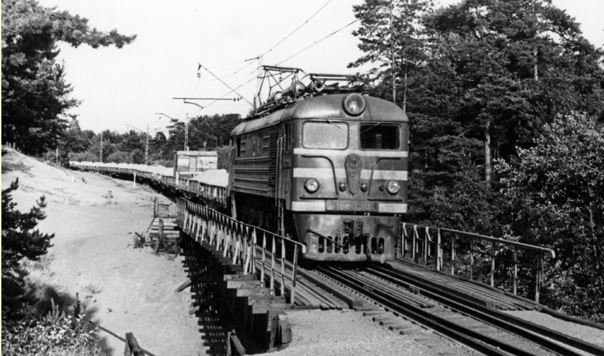 Электровоз ВЛ23-181 с грузовым поездом на мосту через Малую Сестру, около платформы Курорт Сестрорецкой ветки. Хорошо заметен усиленный (двойной) контактный провод, – единственный фрагмент на всём Сестрорецком направлении. Фото: Погодин С.Л., 1993 г.