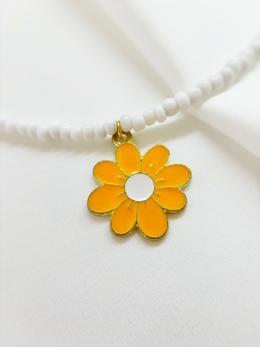 В центре чокера расположена эмалированная ромашка с ярко-желтыми лепестками и белым центром, окруженная золотым контуром, что придает ей объем и выразительность.