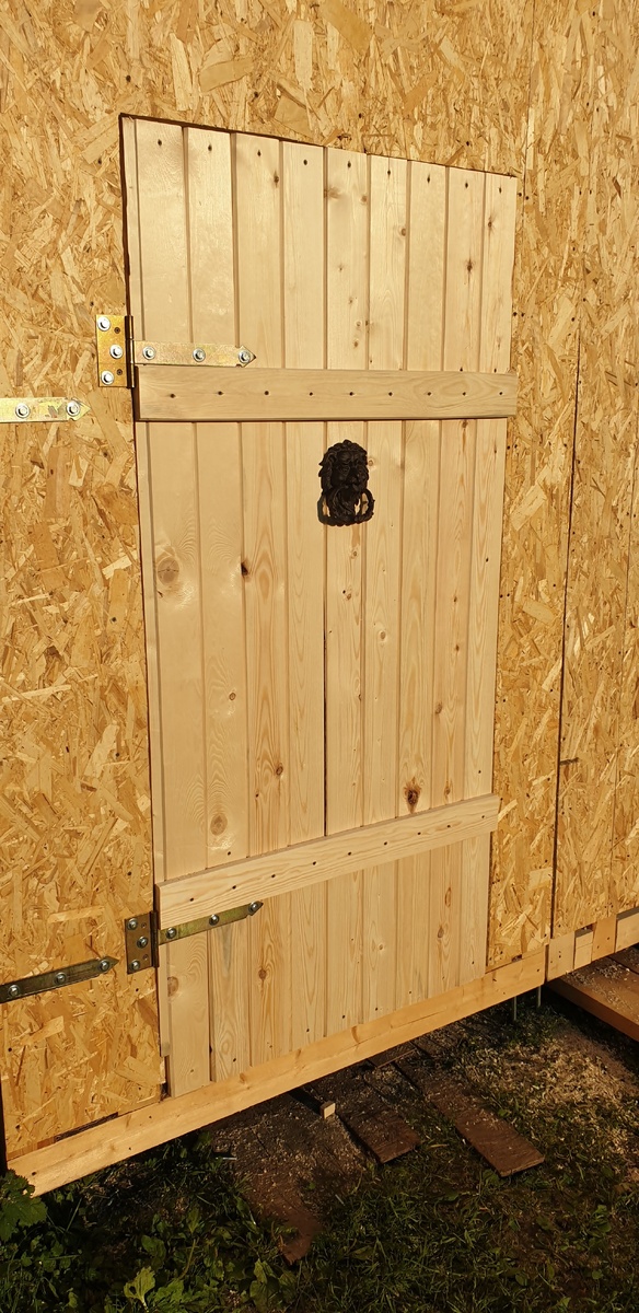 Дверь-калитка в гараж держится на двух усиленных петлях, задекорирована досками 10 мм