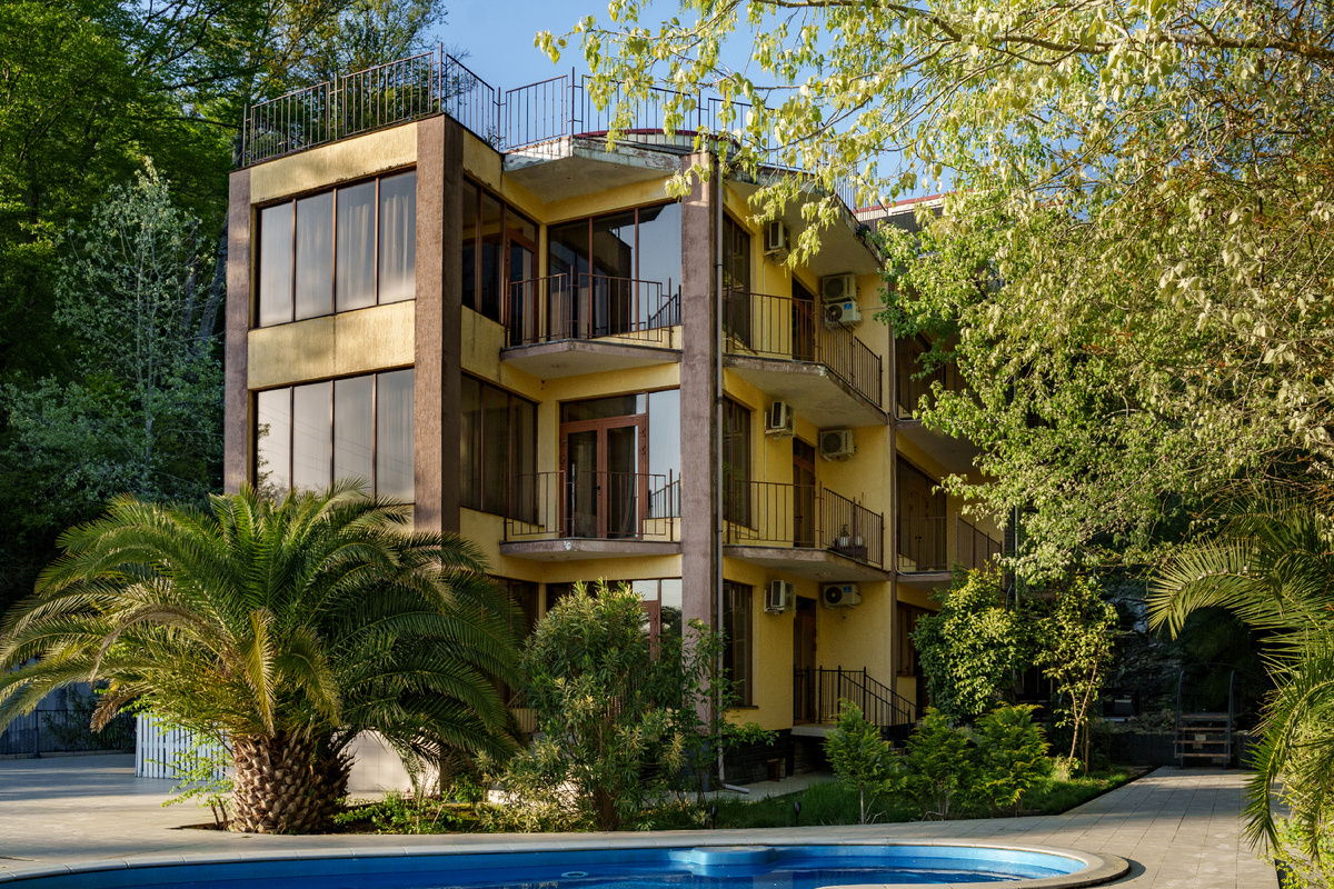 Трехэтажный дом в ущелье среди гор и леса