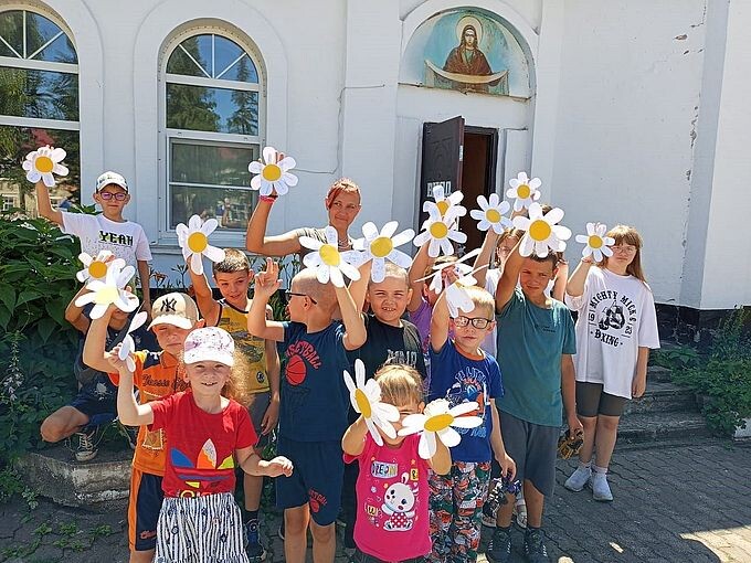 Дети показывают изготовленные ими ромашки из бумаги